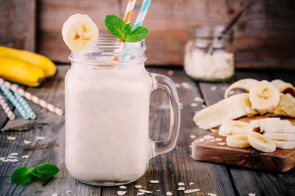 Batido de plátano con avena en tarro de albañil sobre fondo de madera —  Fotos de Stock