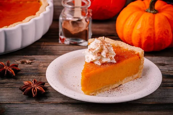 Tarta de calabaza casera para Acción de Gracias con crema batida y canela sobre fondo de madera —  Fotos de Stock