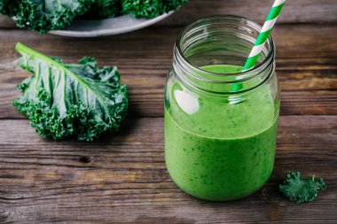 Kale ahşap arka plan üzerinde mason kavanoza ile sağlıklı yeşil smoothie