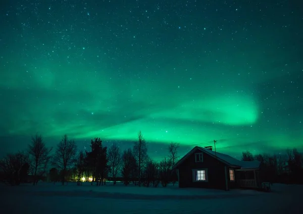 Northern lights (Aurora Borealis) over  cottage in Lapland village. Finland — Stock Photo, Image