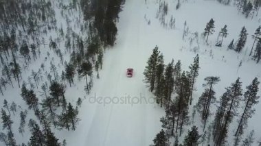 Sadece kırmızı araba hava görünümünü Lapland güzel kış manzara bir kar yağışı sırasında yolda. Doğrusal izleme arabanın. Hava video. 