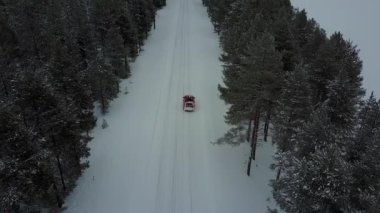 Sadece kırmızı araba hava panoramik manzaralı Lapland güzel kış manzara bir kar yağışı sırasında yolda. Emekli araba izleme. Hava video.