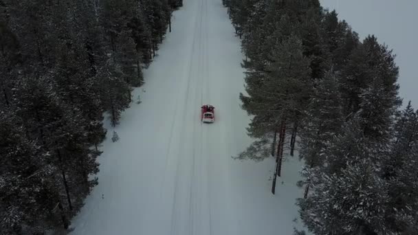 Vista panorámica aérea del único coche rojo en la carretera en el hermoso paisaje de invierno de Laponia durante una nevada. Rastreando un auto retirado. Vídeo aéreo . — Vídeos de Stock