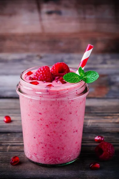 Pink pomegranate smoothie in a glass jar with mint and fresh raspberries — Stock Photo, Image