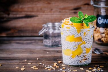 sağlıklı vejetaryen Kahvaltı, mango ve granola ahşap arka plan üzerinde kavanoza chia pudingle