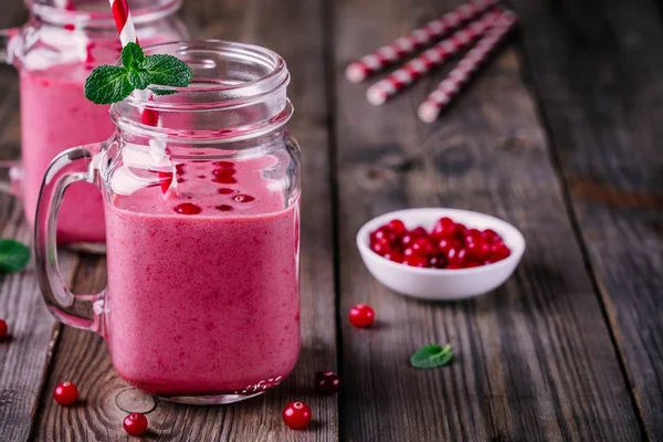 Pink smoothie with wild cranberries in mason jar with mint and straw on wooden background — Stock Photo, Image