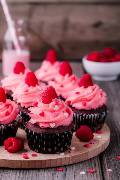 Cupcakes de chocolate com creme rosa, corações de açúcar e framboesas frescas para o Dia dos Namorados — Fotografia de Stock