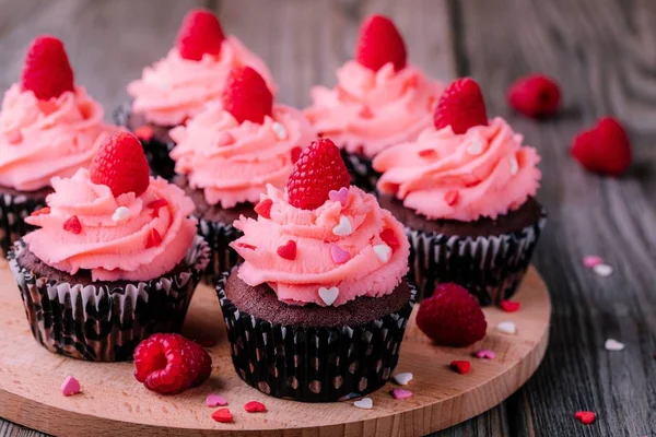 Cupcakes de chocolate con crema rosa, corazones de azúcar y frambuesas frescas para el Día de San Valentín — Foto de Stock