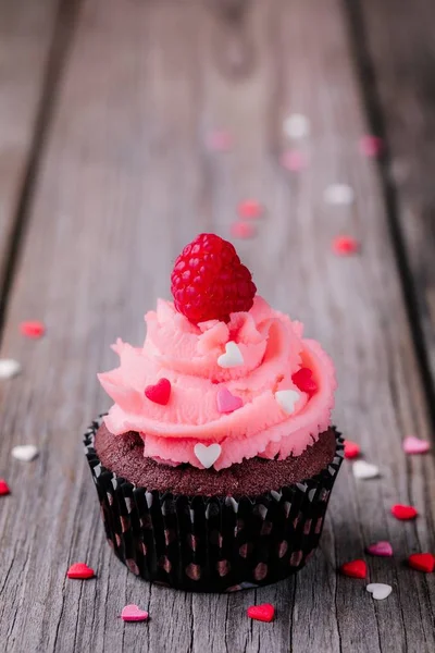 Cupcakes de chocolate com creme rosa, corações de açúcar e framboesas frescas para o Dia dos Namorados — Fotografia de Stock