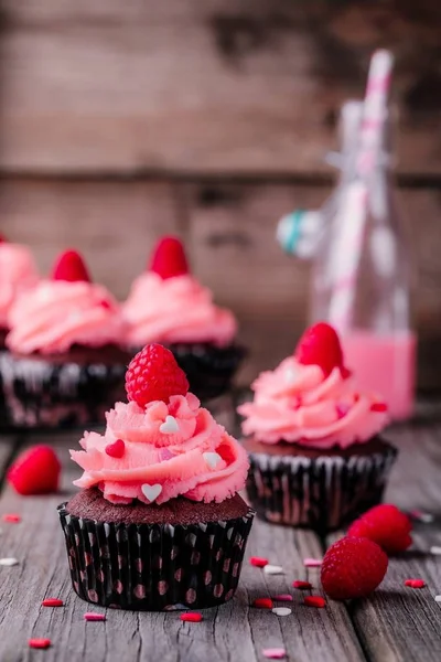 Cupcakes de chocolate com creme rosa, corações de açúcar e framboesas frescas para o Dia dos Namorados — Fotografia de Stock