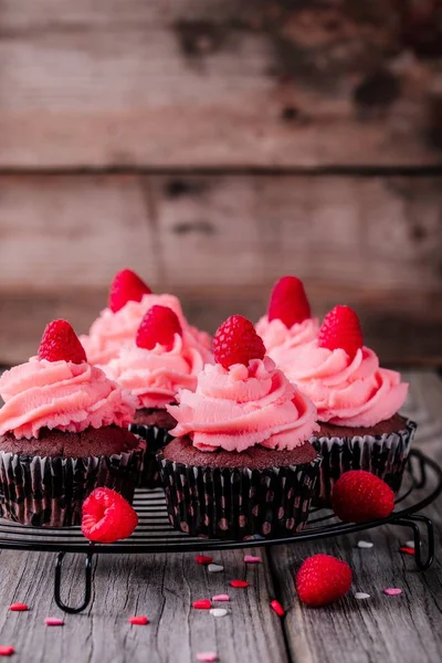 Cupcakes de chocolate con crema rosa, corazones de azúcar y frambuesas frescas para el Día de San Valentín —  Fotos de Stock