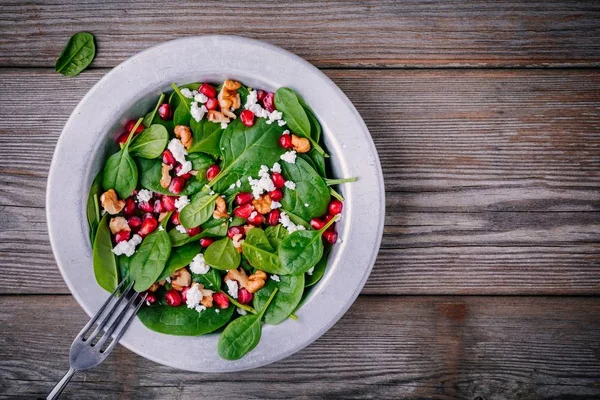 Salada verde fresca com espinafre, nozes, queijo feta e romã — Fotografia de Stock