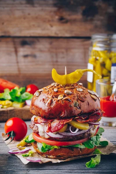 Huisgemaakte hamburger met volkoren broodje, gebakken spek en pikante ingemaakte paprika — Stockfoto