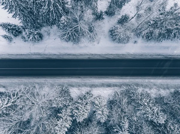 Polna droga przechodzi piękny śnieg pokrywa krajobrazy. Widok z lotu ptaka. — Zdjęcie stockowe
