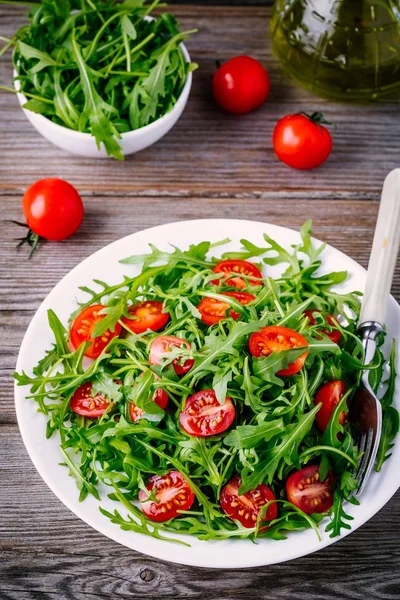 Salada verde fresca com arugula e tomates vermelhos no fundo de madeira — Fotografia de Stock