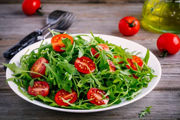 Insalata verde fresca con rucola e pomodori rossi su fondo di legno — Foto Stock