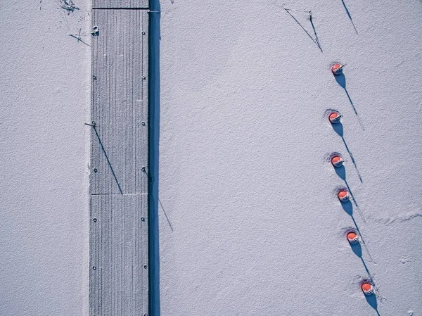 Luchtfoto van de winter bevroren meer met houten pier en rode boeien van bovenaf met een drone gevangen. — Stockfoto