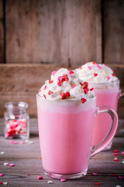 Pink hot chocolate with whipped cream and sugar hearts in a glass mug for Valentine Day