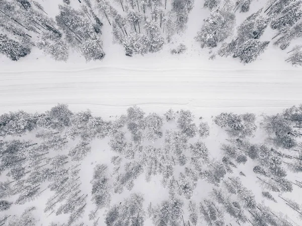 Повітряний безпілотник вид на зимовий ліс і дорогу, вкриту снігом . — стокове фото