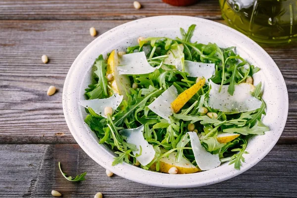 Ensaladera verde de rúcula con pera, queso parmesano y piñones —  Fotos de Stock