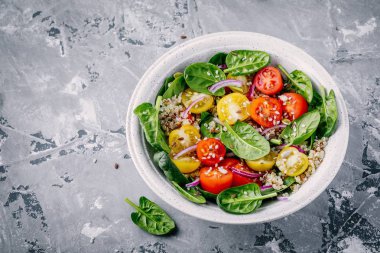 Ispanak, quinoa, sarı ve kırmızı domates, soğan ve tohum ile sağlıklı yeşil kase salata