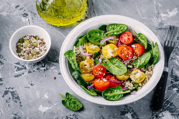 Salade verte saine aux épinards, quinoa, tomates jaunes et rouges, oignons et graines — Photo