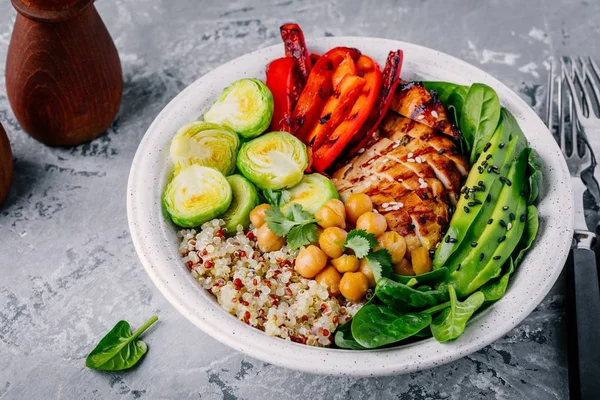Vegetable bowl lunch with grilled chicken and quinoa, spinach, avocado, brussels sprouts, paprika and chickpea