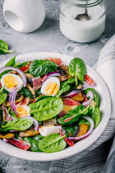 Салат из шпината с беконом, грибами, яйцами и красным луком — стоковое фото