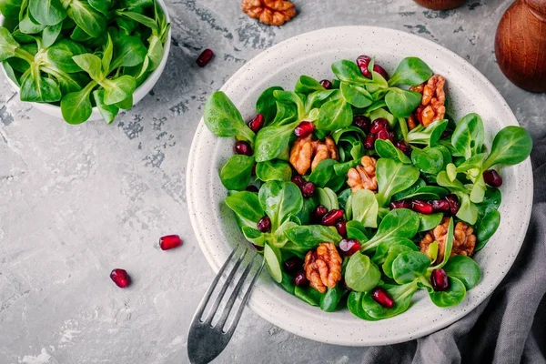 Healthy green Lamb’s lettuce salad with walnuts and pomegranate seeds — Stock Photo, Image
