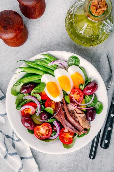 Nicoise-Salat mit Thunfisch, Sardellen, Eiern, grünen Bohnen, Oliven, Tomaten, roten Zwiebeln und Salatblättern — Stockfoto