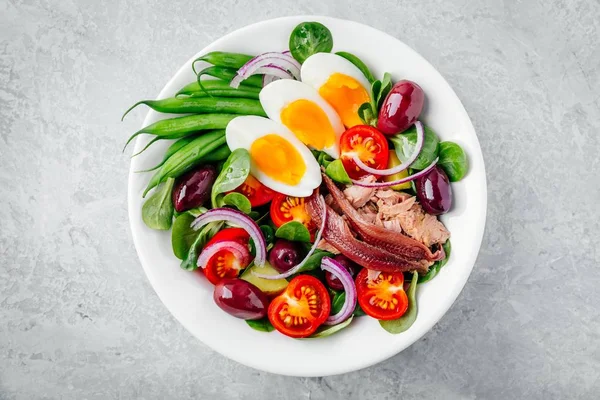 Nicoise-Salat mit Thunfisch, Sardellen, Eiern, grünen Bohnen, Oliven, Tomaten, roten Zwiebeln und Salatblättern — Stockfoto