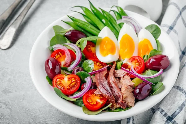 Nicoise-Salat mit Thunfisch, Sardellen, Eiern, grünen Bohnen, Oliven, Tomaten, roten Zwiebeln und Salatblättern — Stockfoto