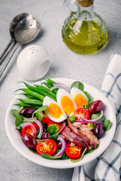 Салат с тунцом, анчоусами, яйцами, зеленой фасолью, оливками, помидорами, красным луком и листьями салата — стоковое фото