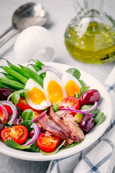 Salată de nicoise cu ton, anșoa, ouă, fasole verde, măsline, roșii, ceapă roșie și frunze de salată — Fotografie, imagine de stoc