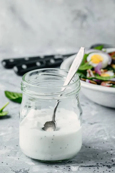 Vallmofrö salladsdressing (sås ranch) i ett glas med spenatsallad i bakgrunden — Stockfoto