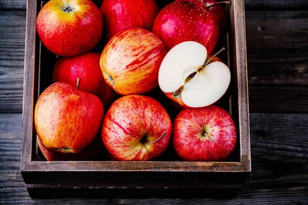 Rode rijpe appels in een vak op een houten achtergrond — Stockfoto