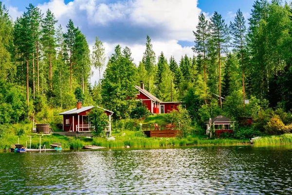 Perinteinen suomalainen puinen mökki, jossa on sauna ja lato järven rannalla. Suomen maaseutu kesällä . — kuvapankkivalokuva