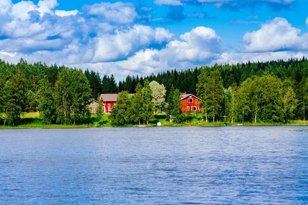 Uma tradicional casa de madeira finlandesa com uma sauna e um celeiro na margem do lago. Verão rural Finlândia . — Fotografia de Stock