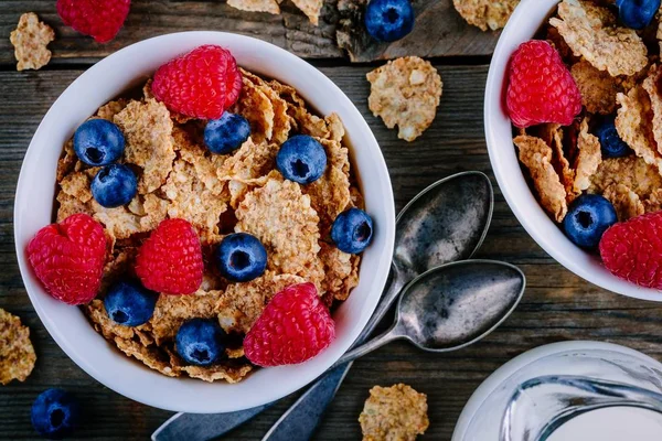 A healthy breakfast bowl. Whole grain cereal with fresh blueberries and raspberries on wooden background. Top view — Stock Photo, Image