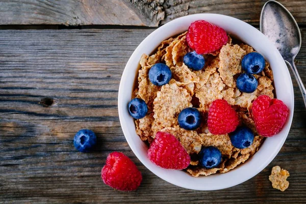 一个健康的早餐碗。全谷类谷物, 新鲜蓝莓和覆盆子在木质背景。顶部视图 — 图库照片