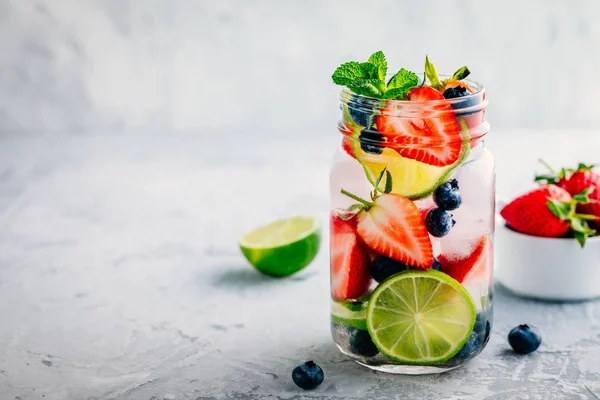 Água de desintoxicação infundida com mirtilo, morango, limão e hortelã. Cocktail frio de verão ou limonada . — Fotografia de Stock