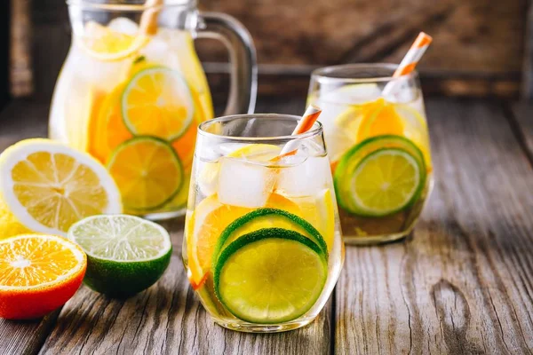 Minuman dingin musim panas yang menyegarkan. Anggur putih sangria dalam gelas dengan kapur, lemon dan oranye — Stok Foto