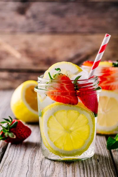 Limão e limonada de morango em frascos de pedreiro de vidro em um fundo de madeira . — Fotografia de Stock