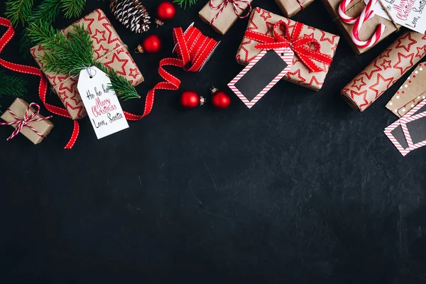 Christmas background with fir branches and cones gift boxes with red bow ribbon on a dark concrete background. — Stock Photo, Image