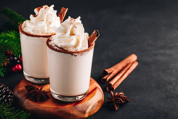 Bebida tradicional de Natal Eggnog com chantilly e canela no fundo de pedra escura . — Fotografia de Stock