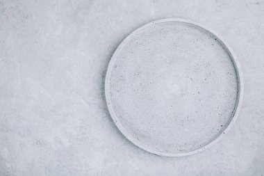 Gri beton zemin üzerinde boş yuvarlak taş plaka, üst görünüm