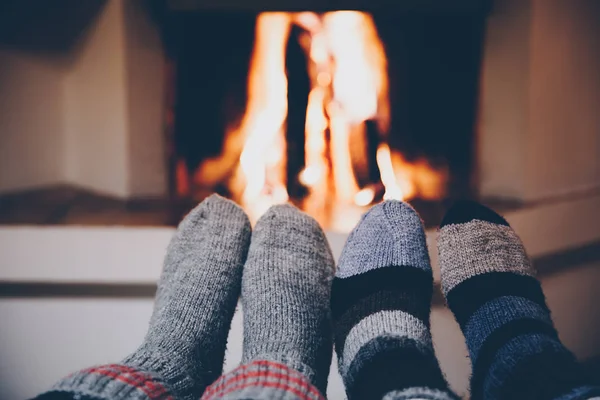 Feet in wool striped socks by the fireplace. Relaxing at Christmas fireplace on holiday evening. — Stock Photo, Image
