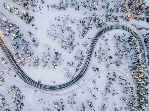 Vista aérea de Curvy Windy Road en el bosque cubierto de nieve en invierno Finlandia —  Fotos de Stock
