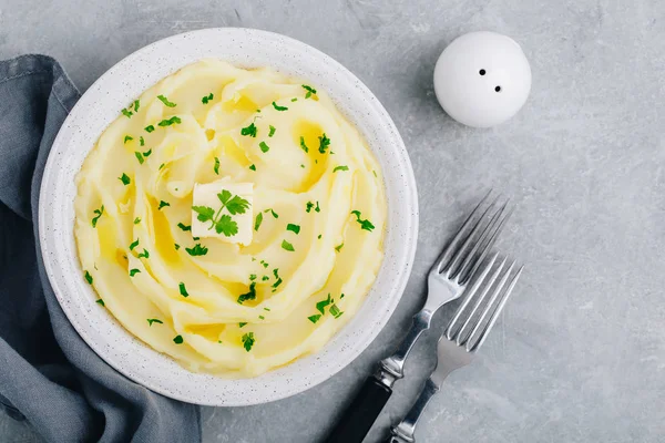 Purè di patate con burro e prezzemolo fresco in una ciotola bianca su sfondo grigio pietra cemento . — Foto Stock