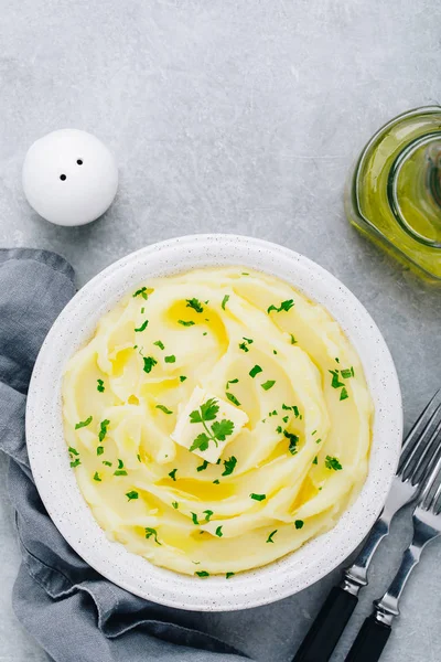 Aardappelpuree met boter en verse peterselie in een witte kom op grijze stenen ondergrond. — Stockfoto